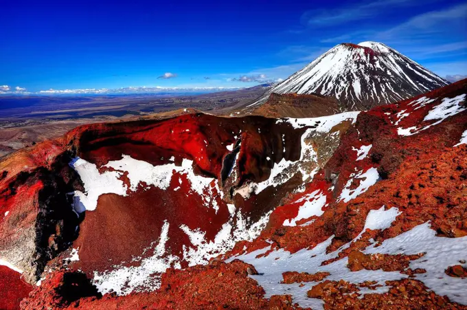 The red crater of the Tongariro volcano, with snow and volcano cone of the Mt. Ngauruhoe.