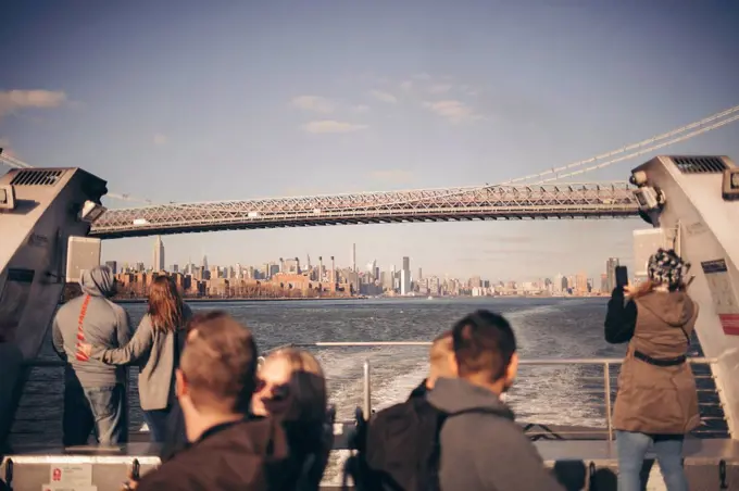 tourists taking pictures from a ferry in brooklyn