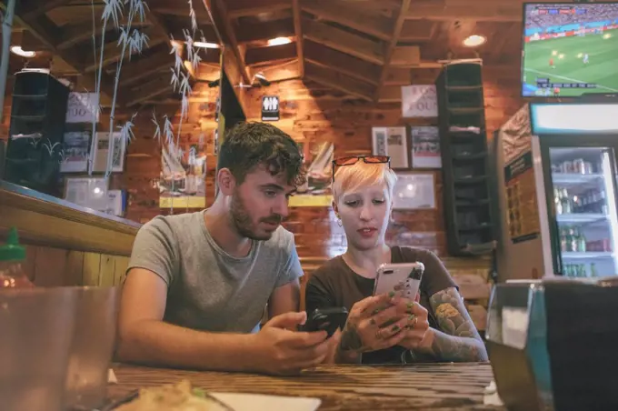 a tourist couple of husband and wife checking their phones on a restaurant