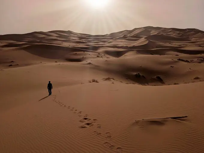 A person walking through the Erg Chebbi desert in the African Sahara, Moroccan desert