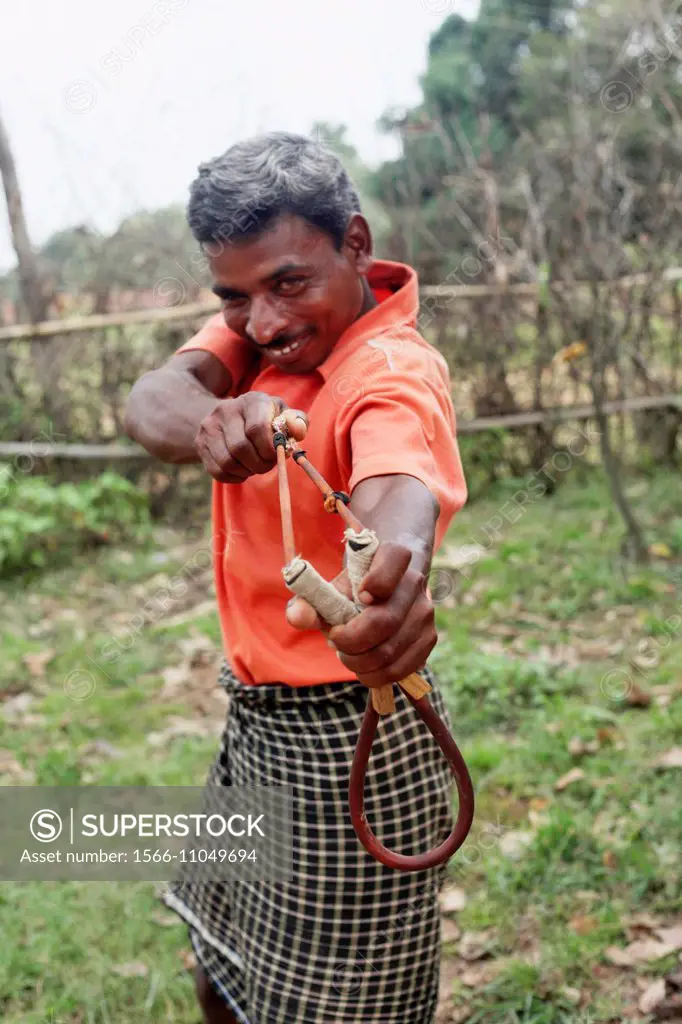 Tribal man using a Gulel (Slingshot) a hunting weapon. Santhal tribe. Jarweadhi village, Bishangarh block, District Hazaribaug, Jharkhand.