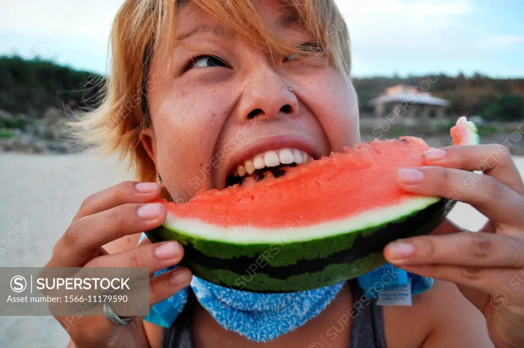 Okinawa, Japan: a woman enjoying a watermelon slice at Odo Beach