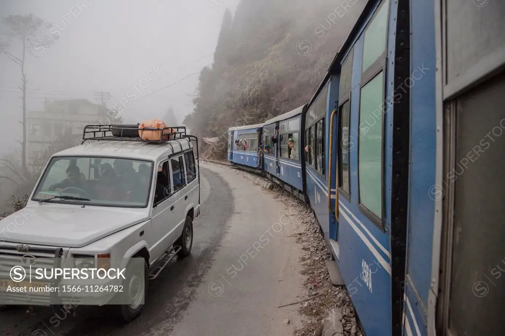 A TATA Sumo taxi on national highway 55 and the Darjeeling Himalayan railway (toy train) in Darjeeling, West Bengal, India. The train and taxi are the...