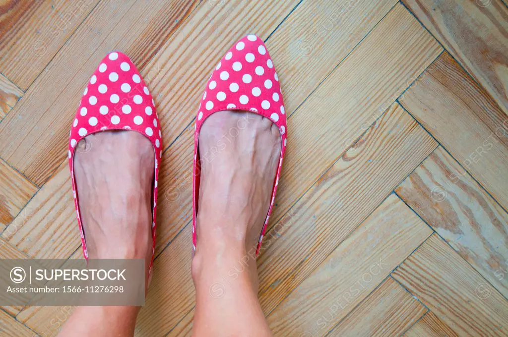 Woman´s feet wearing red shoes with white polka dots. Close view.
