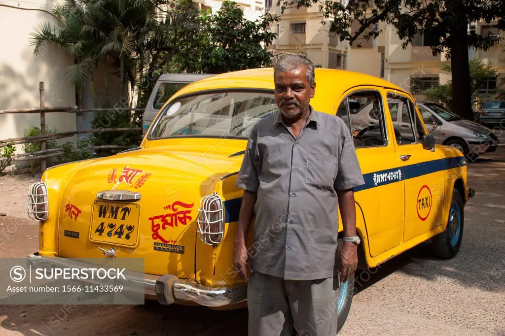 A taxi driver poses near his yellow Ambassador taxi in Kolkata (Calcutta), West Bengal, India.