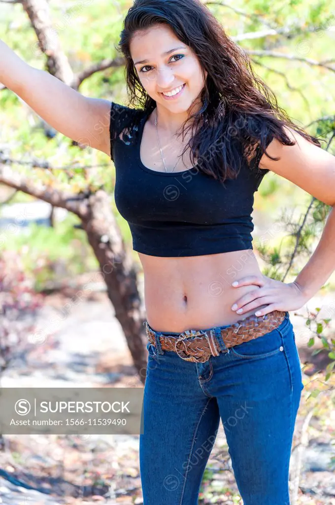 19 year old woman smiling at the camera showing naval and flat stomach wearing a small top