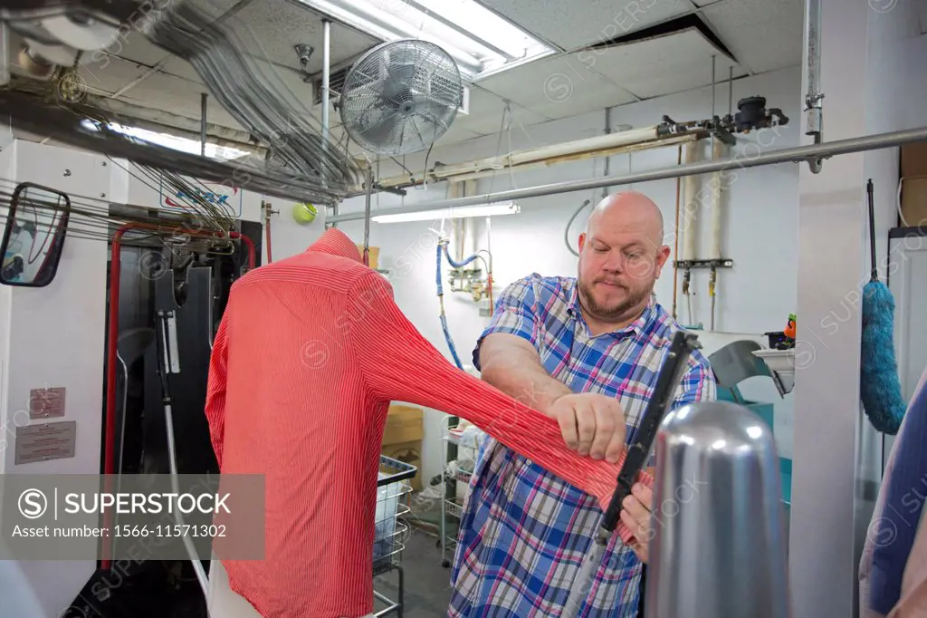 Broomfield, Colorado - A worker at Lionheart Cleaners, a laundry and dry cleaning firm, prepares a shit for a pressing machine.