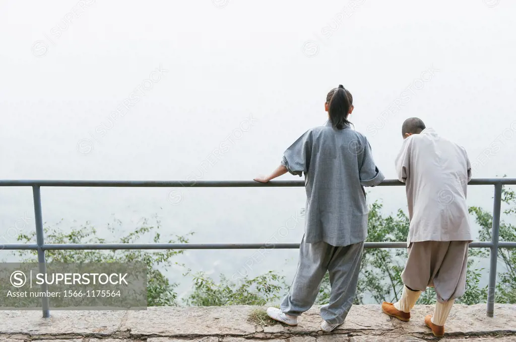 Shaolin nuns stand and perch at a railing at the statue of Bodhidharma at the Shaolin Temple