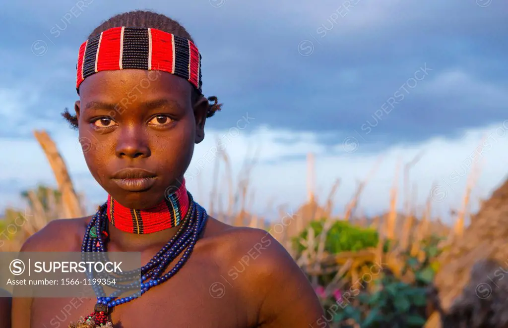 Turmi Ethiopia Africa Lower Omo Valley village with teenage Bena tribe girl portait at sunset in wood hut village 24