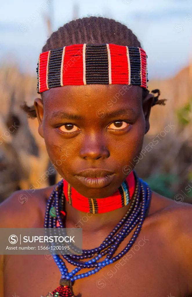 Turmi Ethiopia Africa Lower Omo Valley village with teenage Bena tribe girl portait at sunset in wood hut village 24