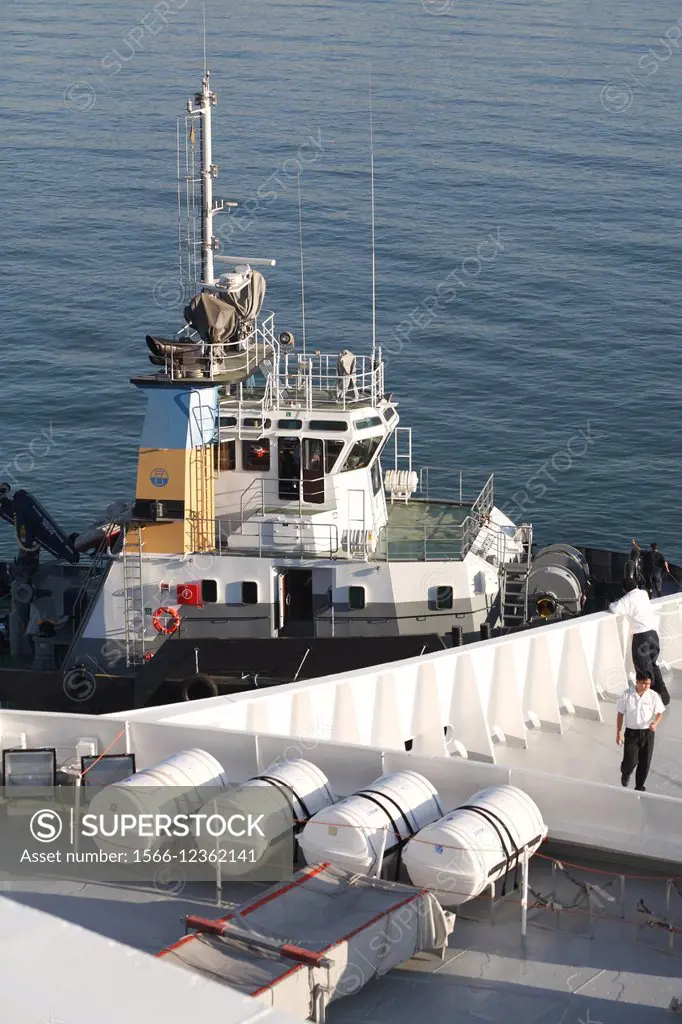 tug helping berth cruise ship (QE2) into position..Spain.