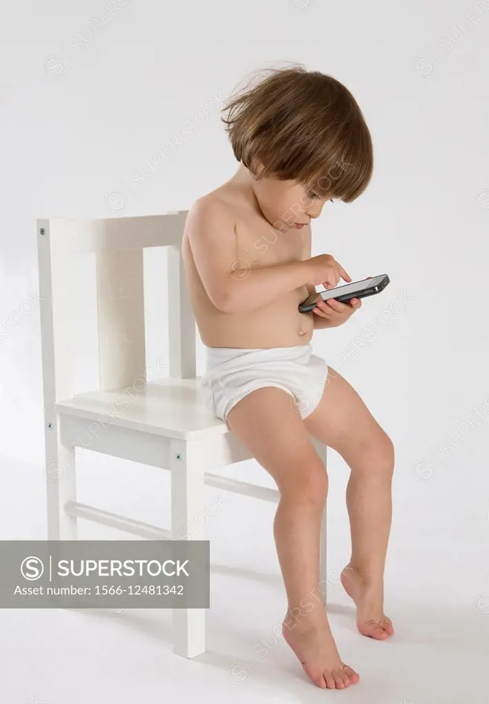 Little girl in underwear sitting on bed looking at smartphone