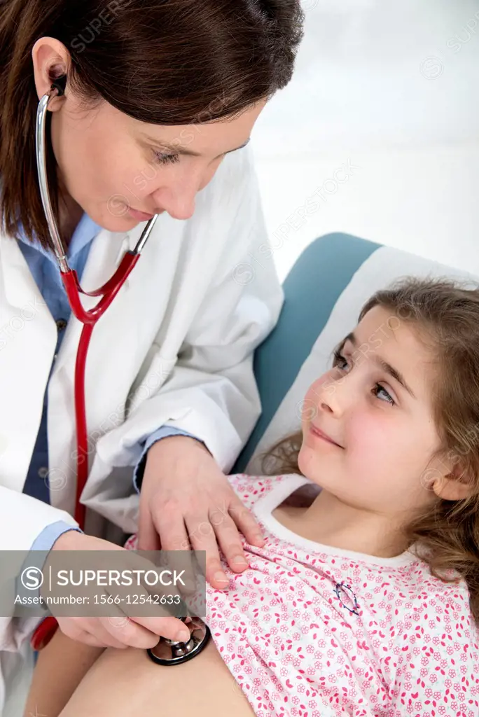 Paediatrcian doctor examining little girl lying on medical couch, with her stethoscope