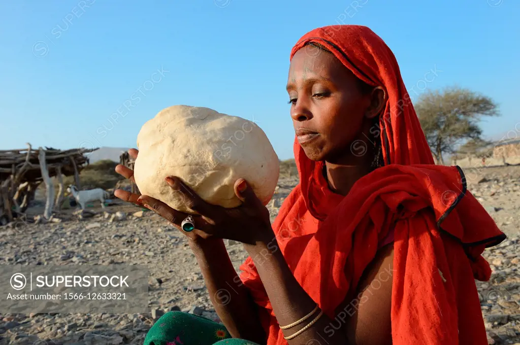 Afar tribe woman kneading a bread loaf before baking it, Malab-Dei village, Danakil depression, Afar region, Ethiopia, Africa.