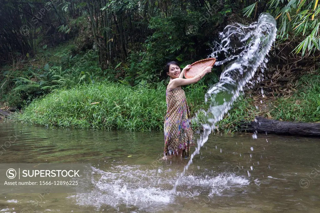 A Bidayuh lady in sarong playing with water, Annah Rais hot spring, Sarawak, Malaysia.