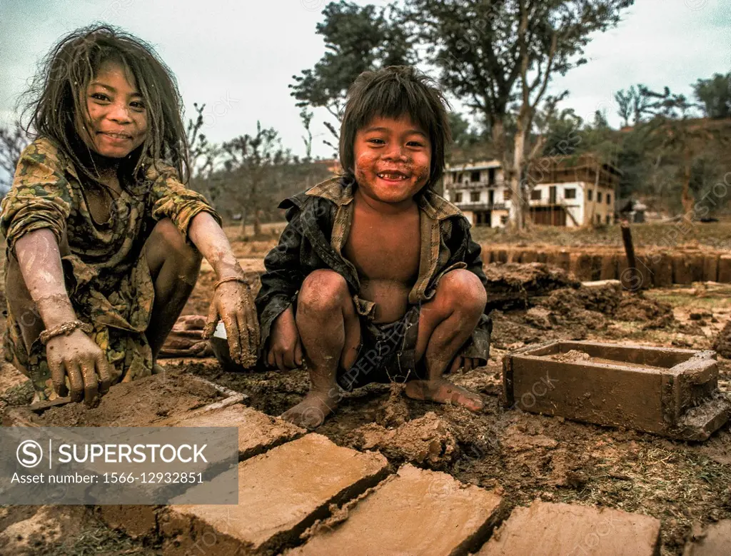 Brother and sister make mud bricks in wooden frame for parents house, Arun  valley, Nepal. - SuperStock