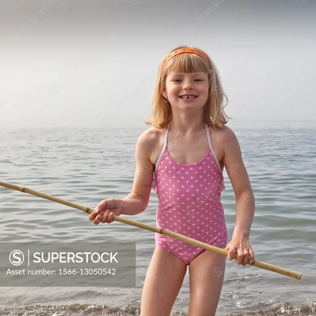 Girl wih fishing net playing at the beach, Akranes, Iceland. - SuperStock