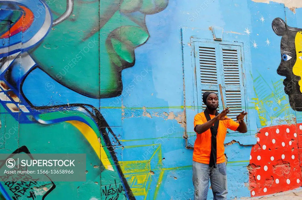 Senegalese graffiti artist Docta beside a collective mural in Medina district, Dakar, Senegal, West Africa.