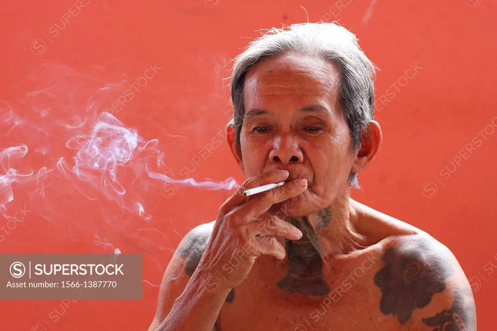 Portrait of Iban old man with traditional tattoo and smoking, malaysia