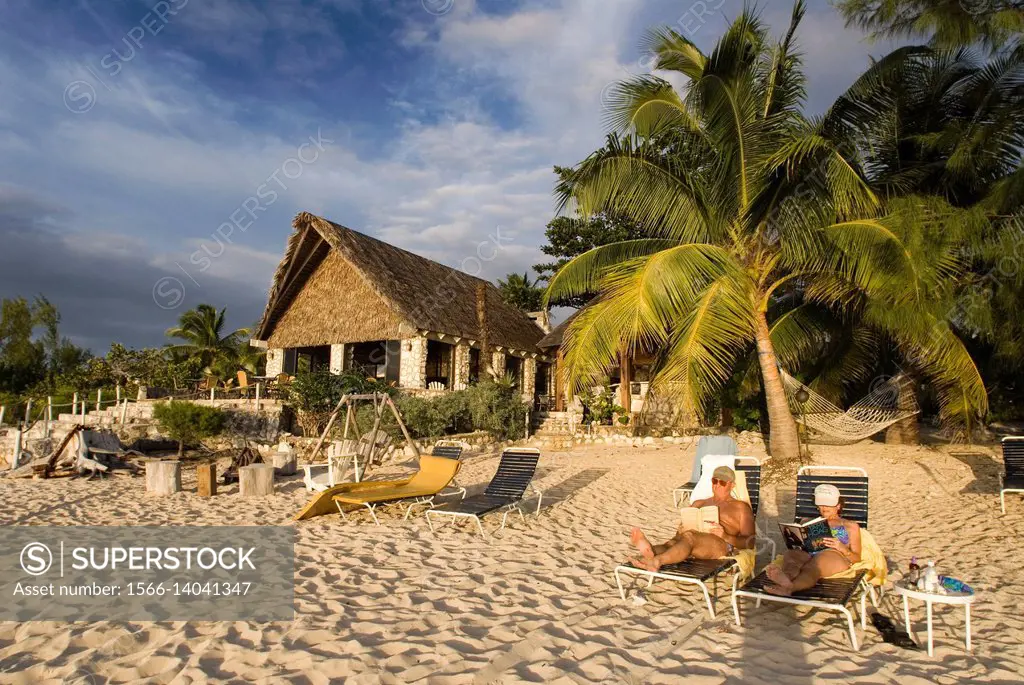 Cat Island, Bahamas. Beachfront cottages. Hotel Fernandez Bay Village resort. Tourists relaxing on the beach.