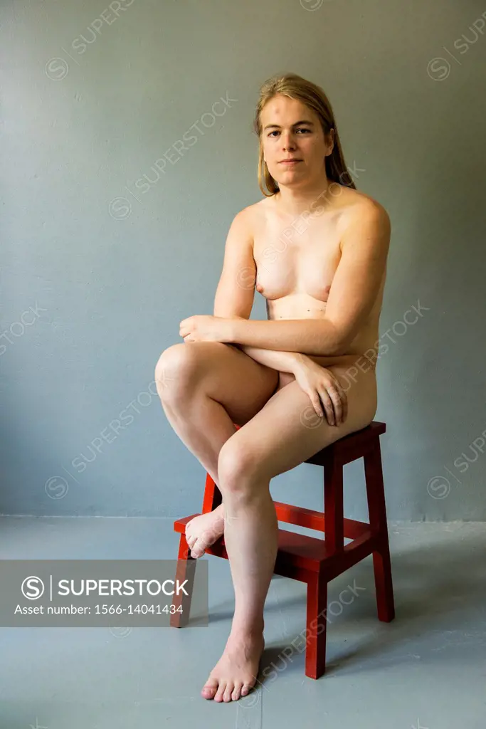 Tilburg, Netherlands. Studio portrait of a young, nude transgender sitting on a stool.