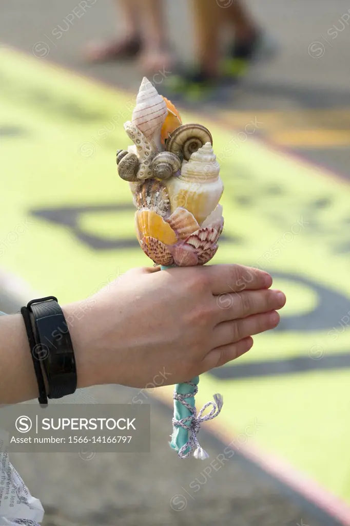 Hand holding a staff made of sea shells.