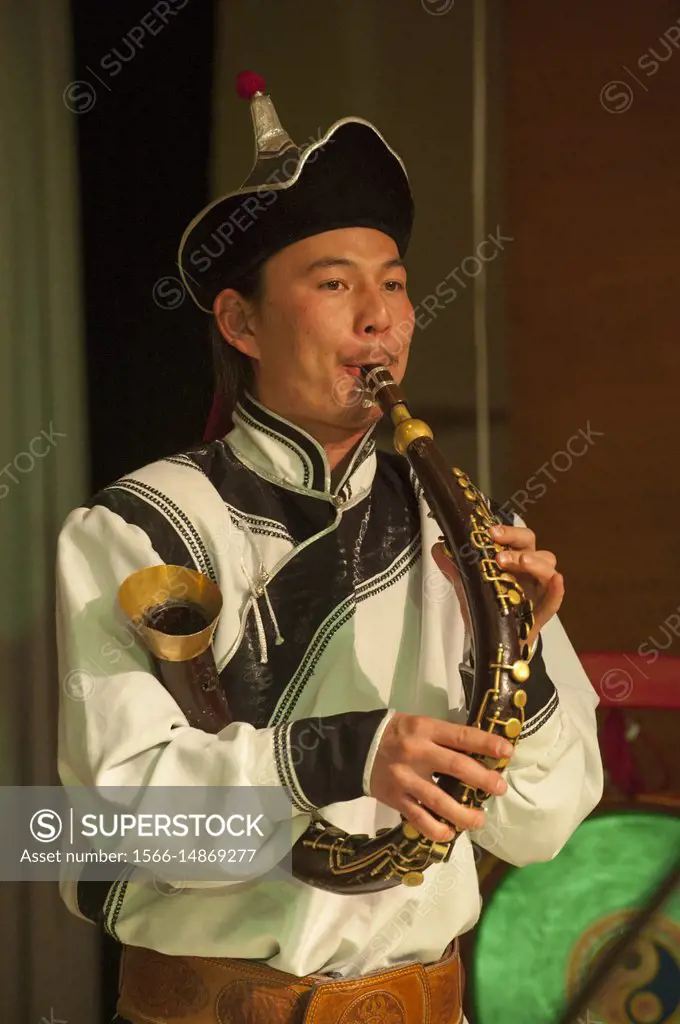 A Mongolian musician is playing the Bishguur, a traditional Mongolian cow horn flute, during a cultural performance in Ulaanbaatar, Mongolia.