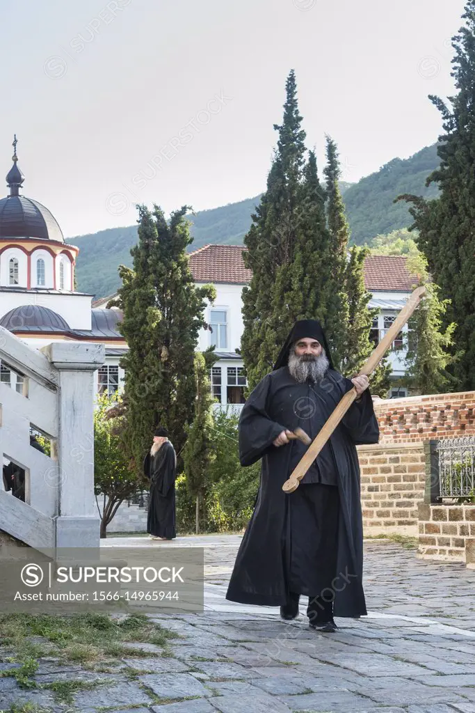 An orthodox monk sounds the call to evening prayer by striking a wooden semantron at the Skete of Saint Andrew at Karyes on The Athos peninsula, Maced...