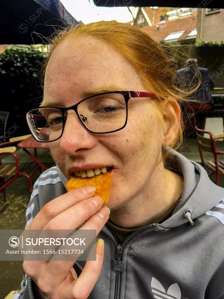 Tilburg, Netherlands. A young, redhaired girl playing horney, while sitting  at a cafe´s terrace with her male company. - SuperStock