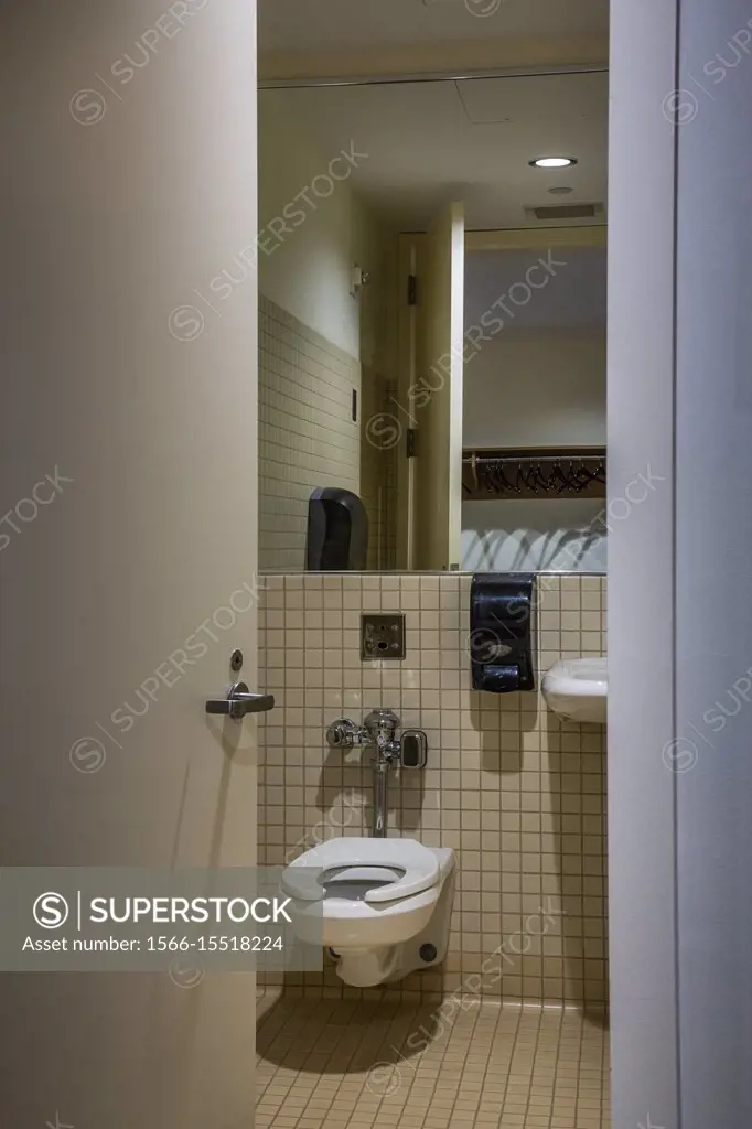 Toilet in an office building seen through a partially open bathroom door.