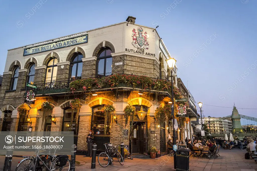 People sitting outdoors in The Rutland Arms pub on the Hammersmith Riverside at dusk, Hammersmith, London, England, UK.