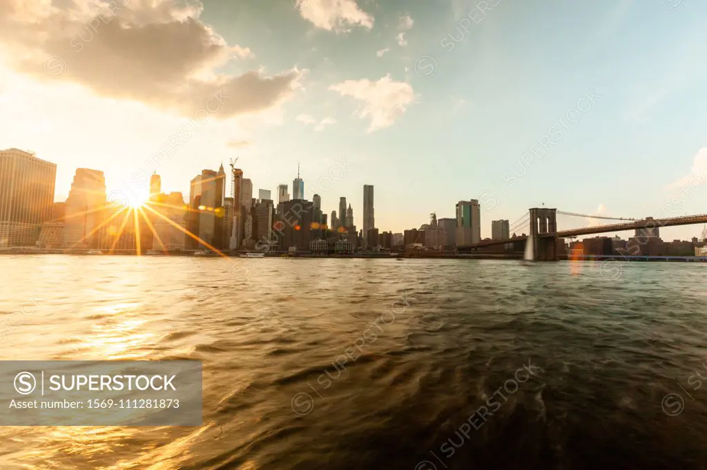 Manhattan city skyline and Brooklyn Bridge at sunset