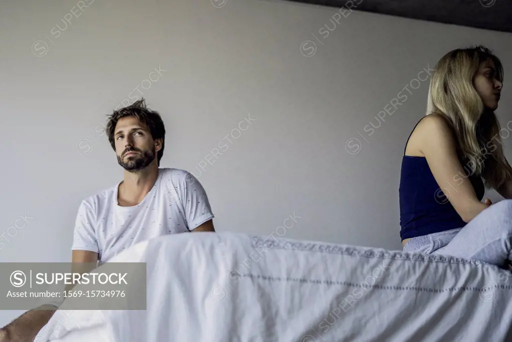 Upset couple sitting in bedroom