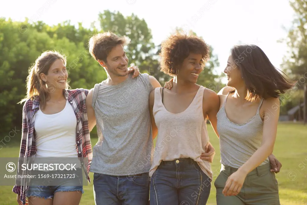 Happy young friends walking together in park