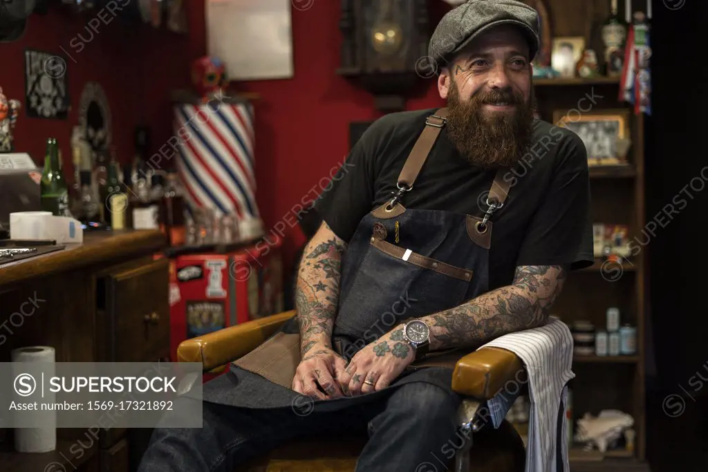 Smiling hairdresser sitting on chair in salon