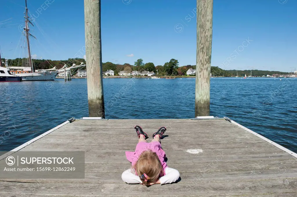 Little girl lying on dock with hands behind head