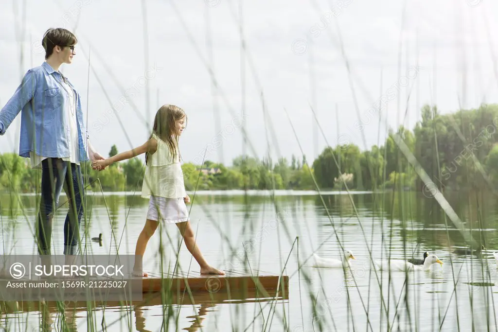 Mother and daughter holding hands on dock