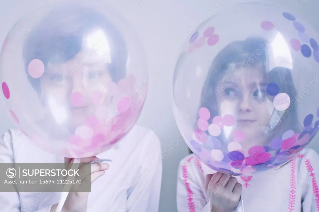 Children hiding behind transparent balloons