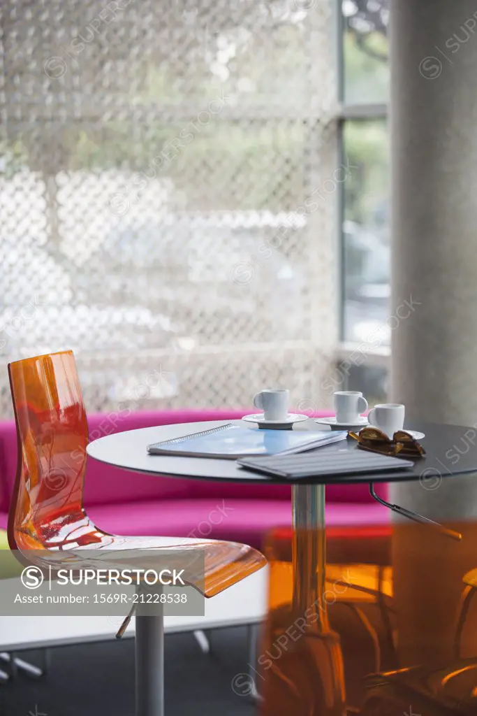 Coffee cups, notebooks, and sunglasses left on table in cafe