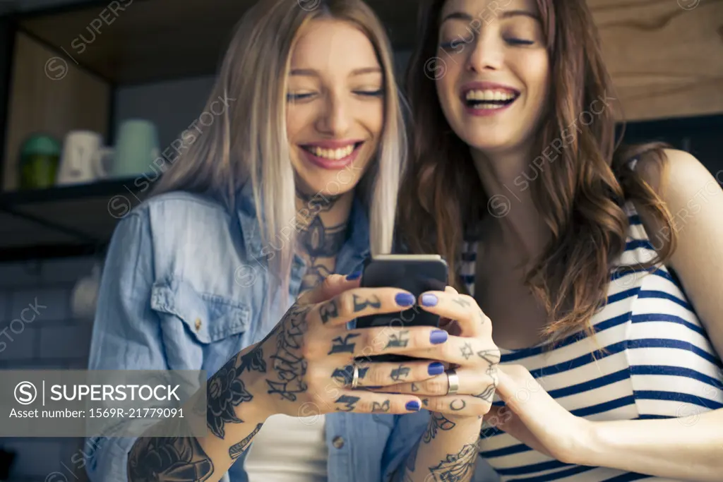 Women looking at smartphone and laughing together