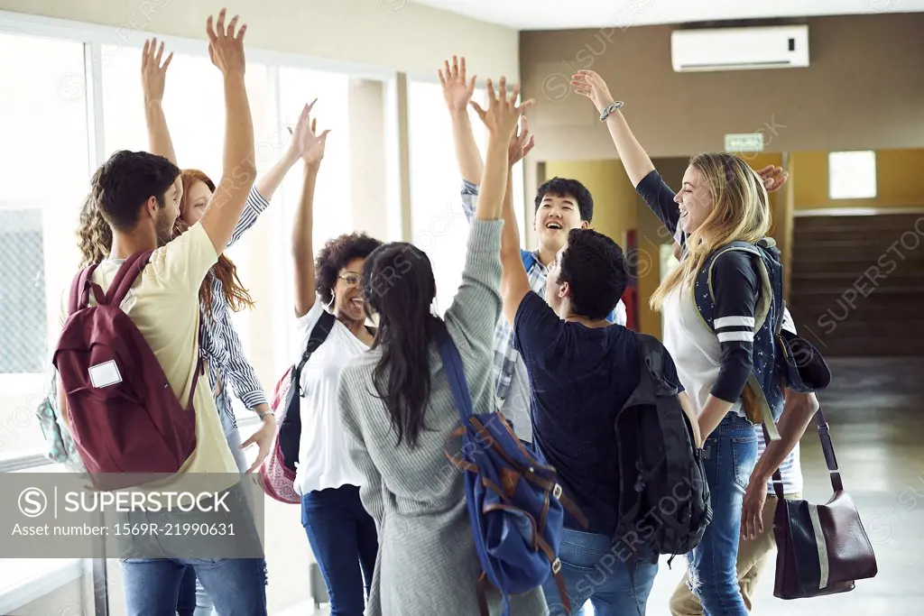 Group of students standing in a circle with hands raised in the air