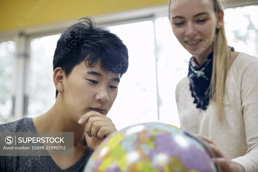 Students looking at globe in classroom