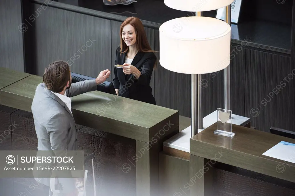 Female receptionist giving credit card to businessman