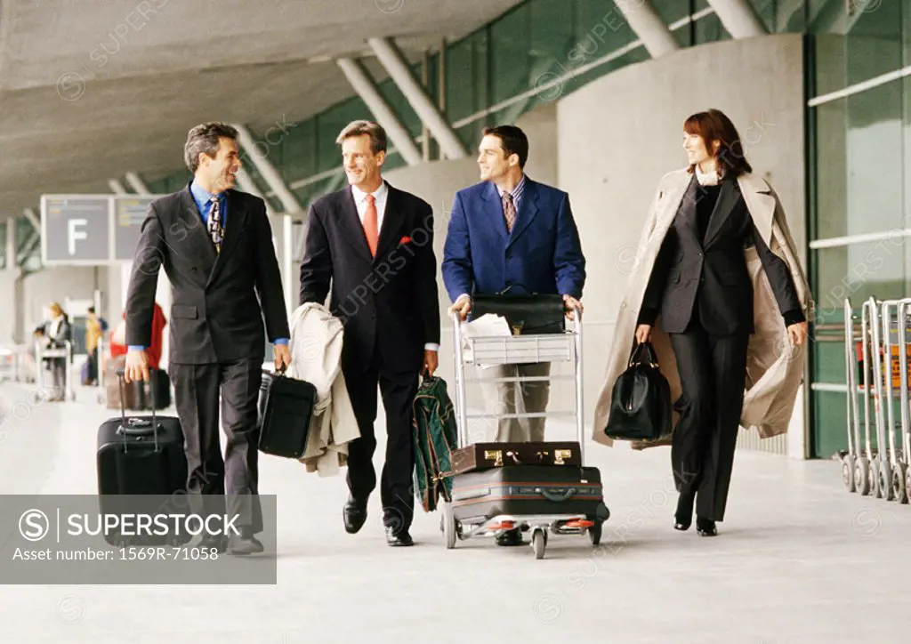 Group of business people walking with luggage outside airport terminal