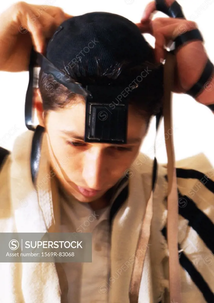 Jewish man putting on Tefillin, close-up