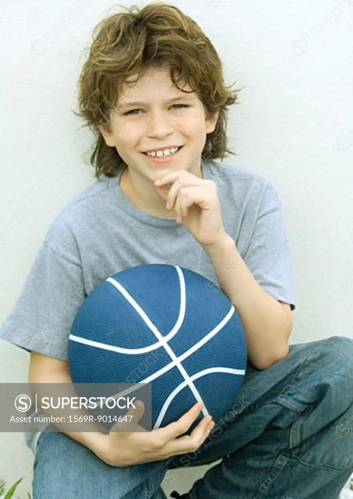 Boy holding basketball, portrait