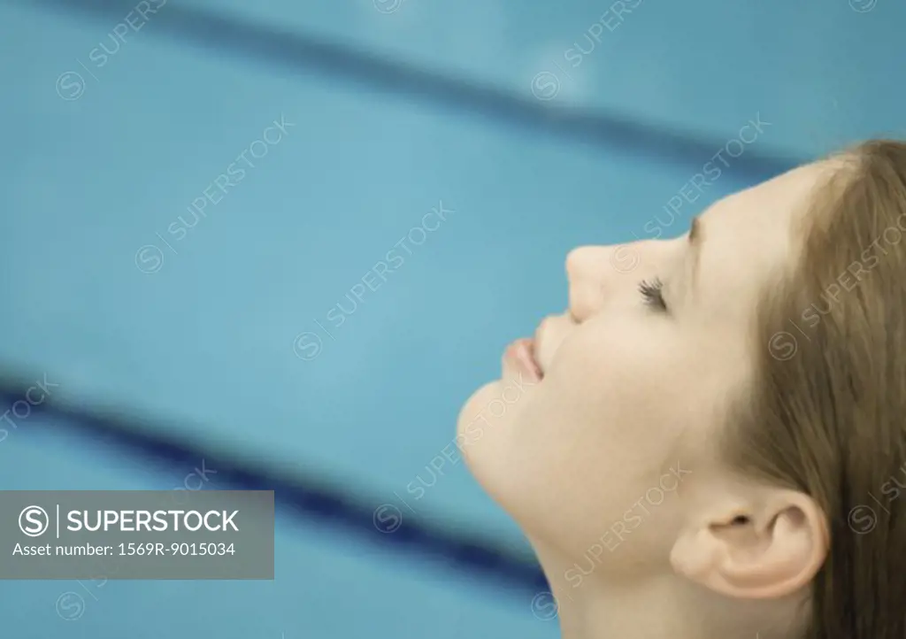 Woman smiling, close-up of side view of face, pool in background