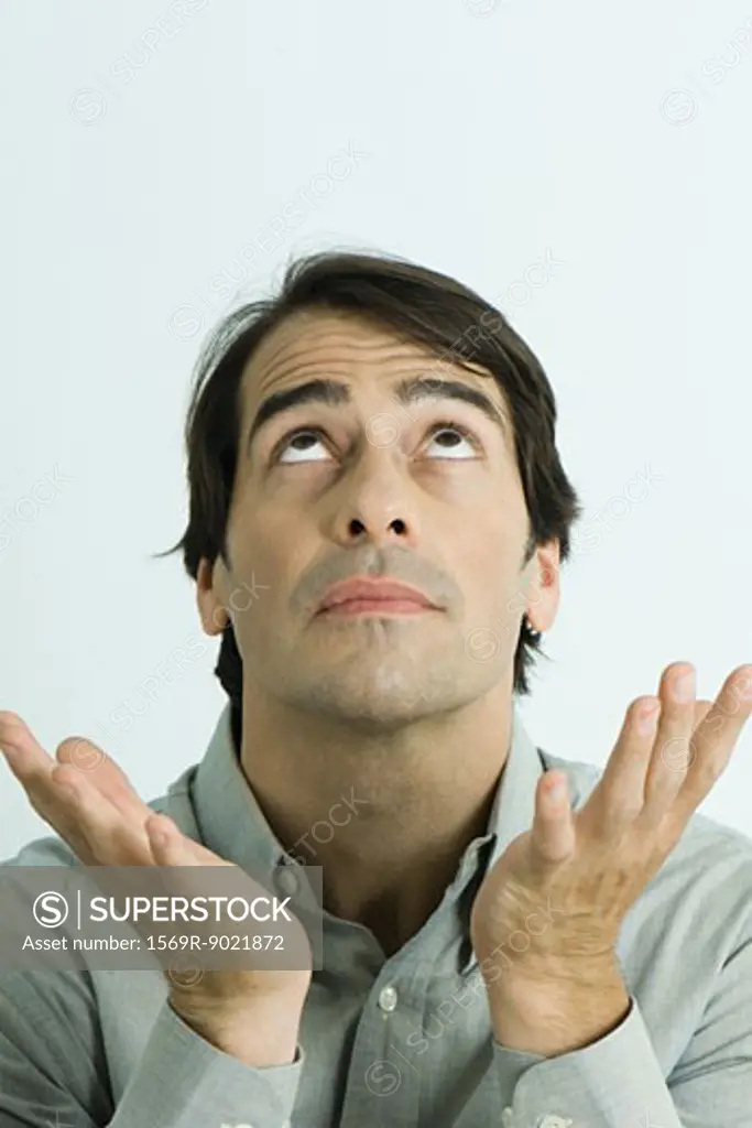 Man looking up and holding up hands, head and shoulders, portrait