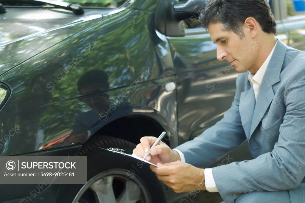 Mature man in suit inspecting car