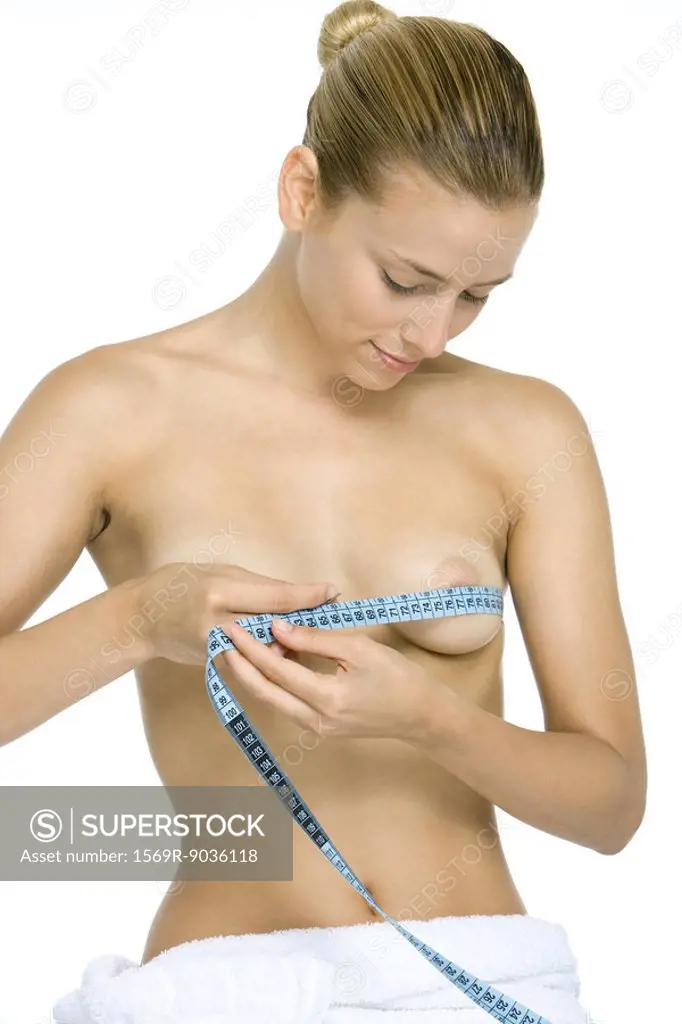 Woman wrapping measuring tape around chest, looking down at